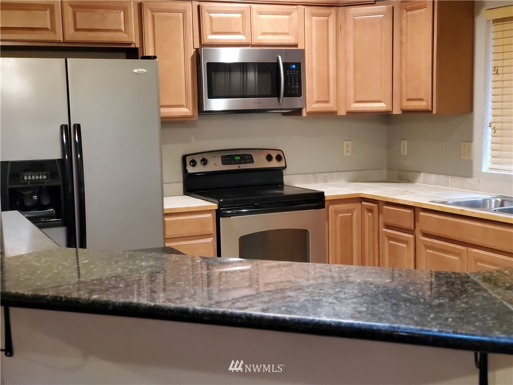 541 East Coulter Creek Road Belfair, WA 98528 - Photo 9 of 39 a kitchen with stainless steel appliances granite countertop a sink a stove and microwave