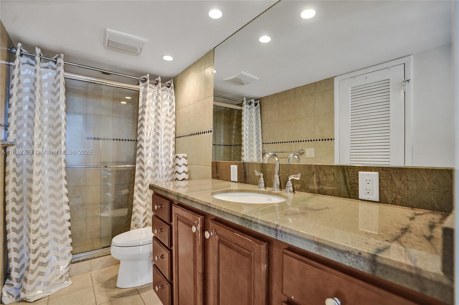 405 North Ocean Boulevard, Unit 815 Pompano Beach, FL 33062 - Photo 27 of 41 a bathroom with a granite countertop sink a toilet a mirror and shower