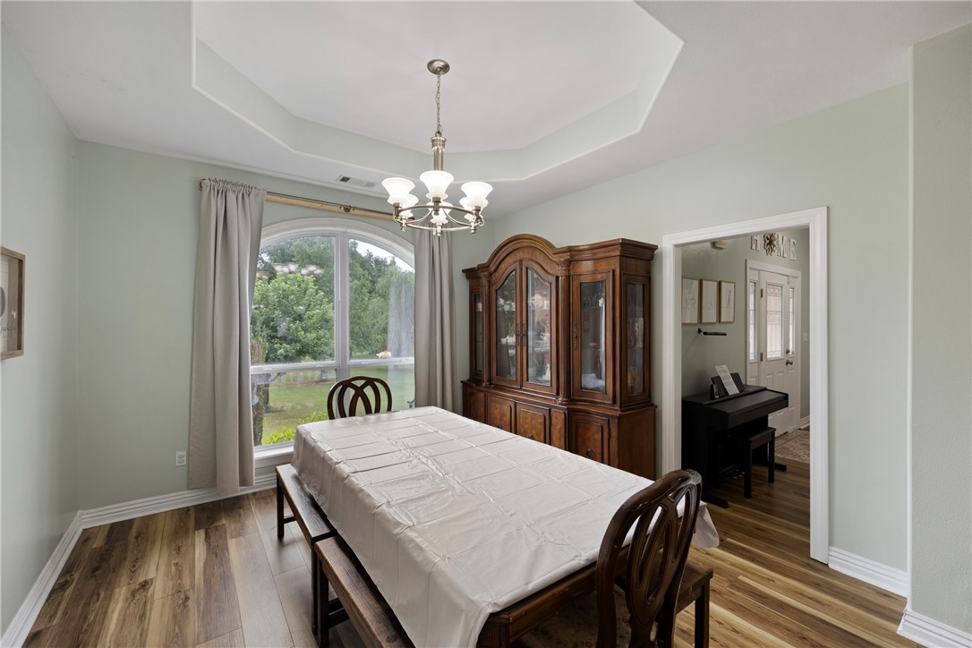751 Walthall Road Russellville, AR 72802 - Photo 12 of 60 Dining area featuring wood-finish flooring, a tray ceiling, and a chandelier