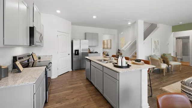 a kitchen with stainless steel appliances granite countertop a table chairs stove and sink