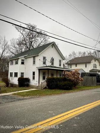 a view of a white house with a large windows next to a road