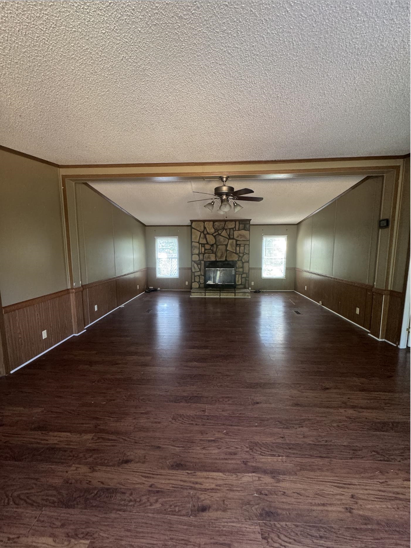 2847 Holly Grove Road Covington, TN 38019 - Photo 3 of 7 Unfurnished living room with wainscoting, a textured ceiling, wooden walls, dark wood-style floors, and a fireplace