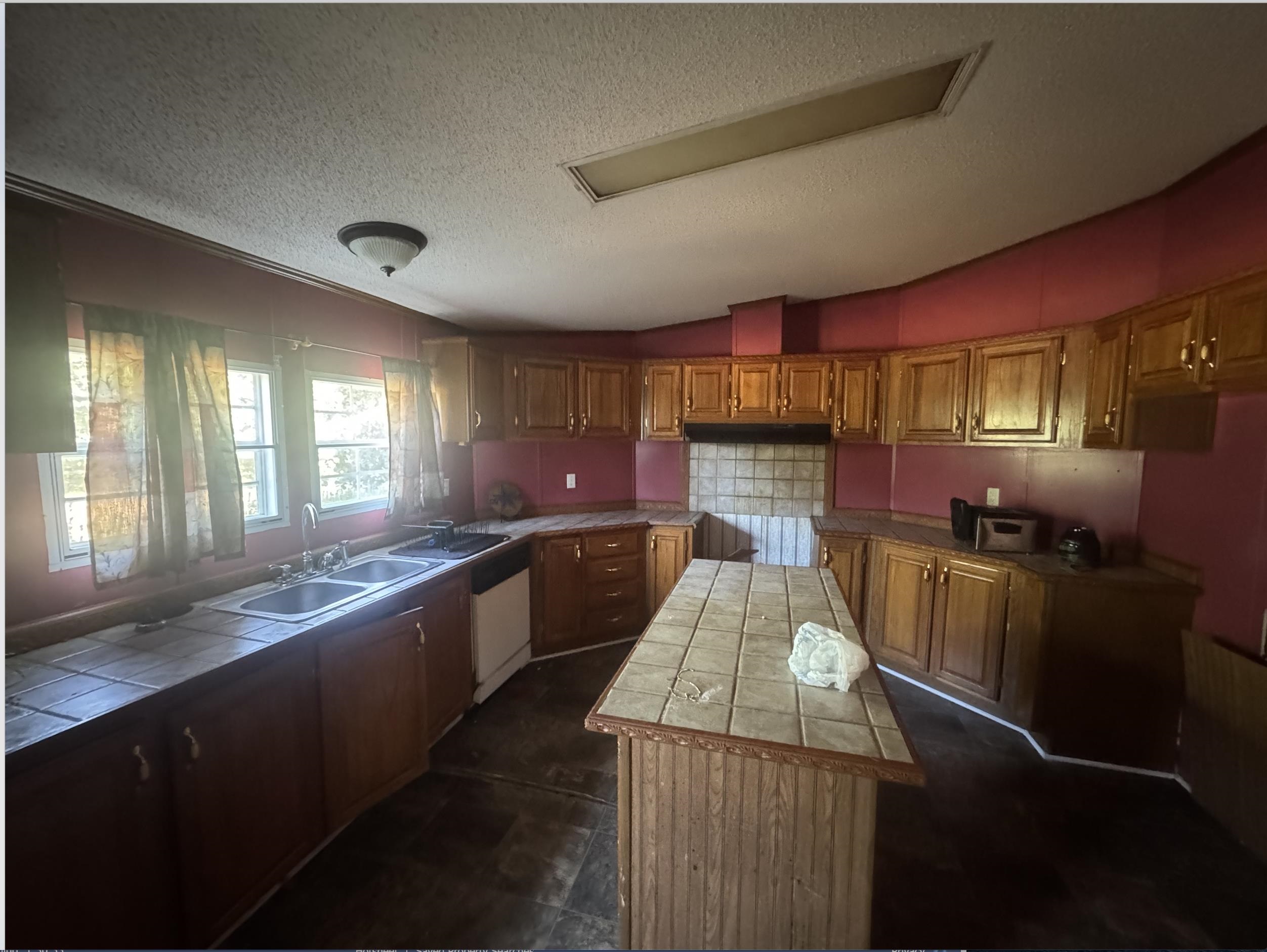 2847 Holly Grove Road Covington, TN 38019 - Photo 4 of 7 Kitchen featuring tile countertops, vaulted ceiling, brown cabinets, a center island, and a textured ceiling