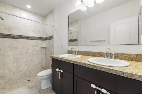 a bathroom with a granite countertop sink a toilet and a mirror
