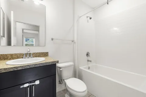 a bathroom with a granite countertop sink toilet a mirror and bathtub