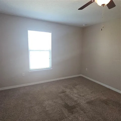 an empty room with a chandelier fan and windows