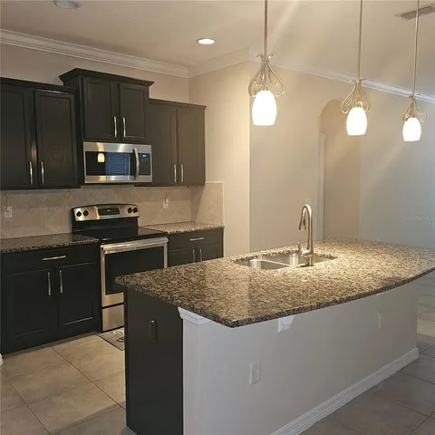 a kitchen with kitchen island granite countertop a sink a counter space appliances and cabinets