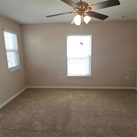 an empty room with a chandelier fan and glass door