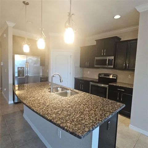 a kitchen with kitchen island granite countertop a sink counter top space appliances and cabinets
