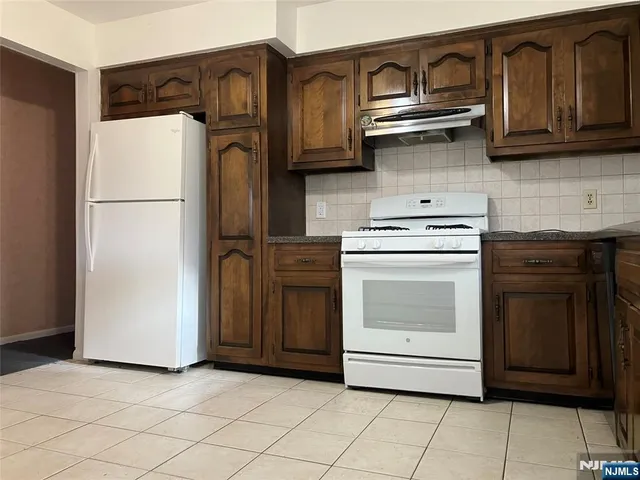 a kitchen with stainless steel appliances granite countertop a refrigerator a stove and a sink