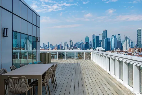 a view of a roof deck with table and chairs a barbeque with wooden floor and fence