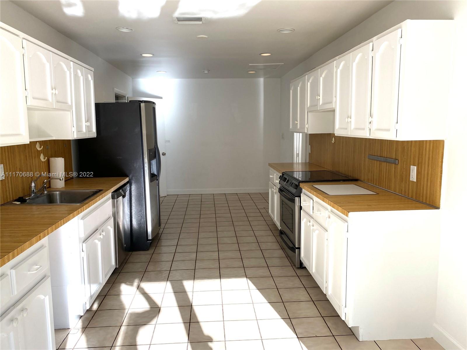 9800 Southwest 70th Avenue Pinecrest, FL 33156 - Photo 6 of 8 a kitchen with a sink a refrigerator and cabinets