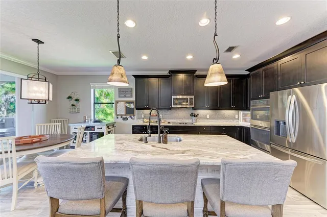 a kitchen with stainless steel appliances granite countertop a refrigerator a stove a sink dishwasher with a dining table and chairs