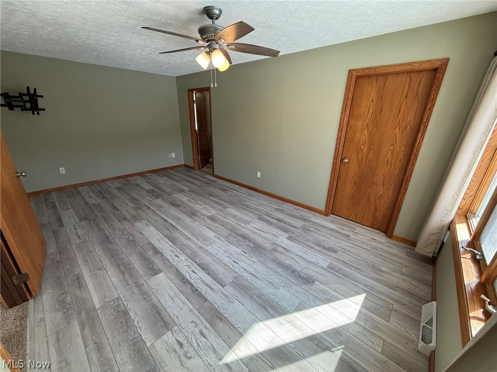 6784 Old Zoarville Road Northeast Dover, OH 44622 - Photo 19 of 50 Unfurnished bedroom with light wood-type flooring, a ceiling fan, and a textured ceiling