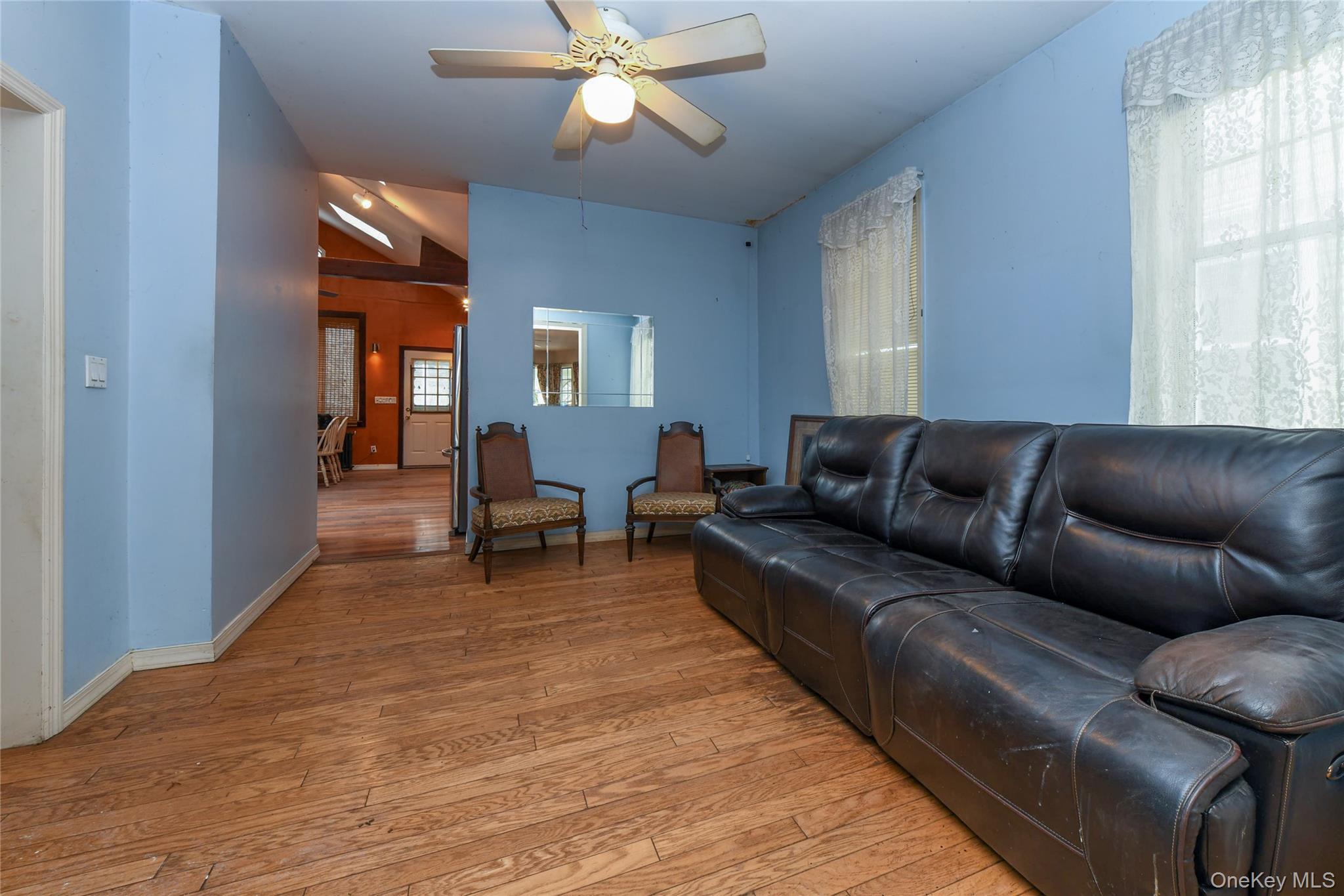 76-43 85th Road Queens, NY 11421 - Photo 11 of 31 a living room with furniture and a dining table with wooden floor