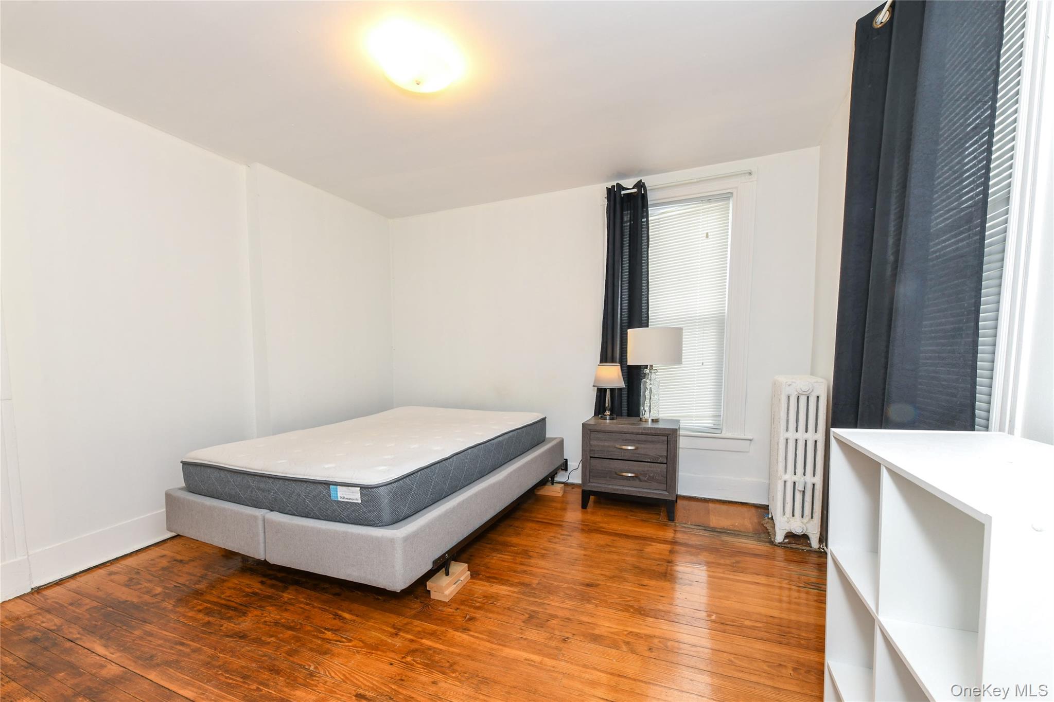 76-43 85th Road Queens, NY 11421 - Photo 22 of 31 a bedroom with a bed and wooden floor