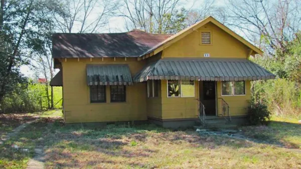 a view of a brick house with a small yard and wooden fence