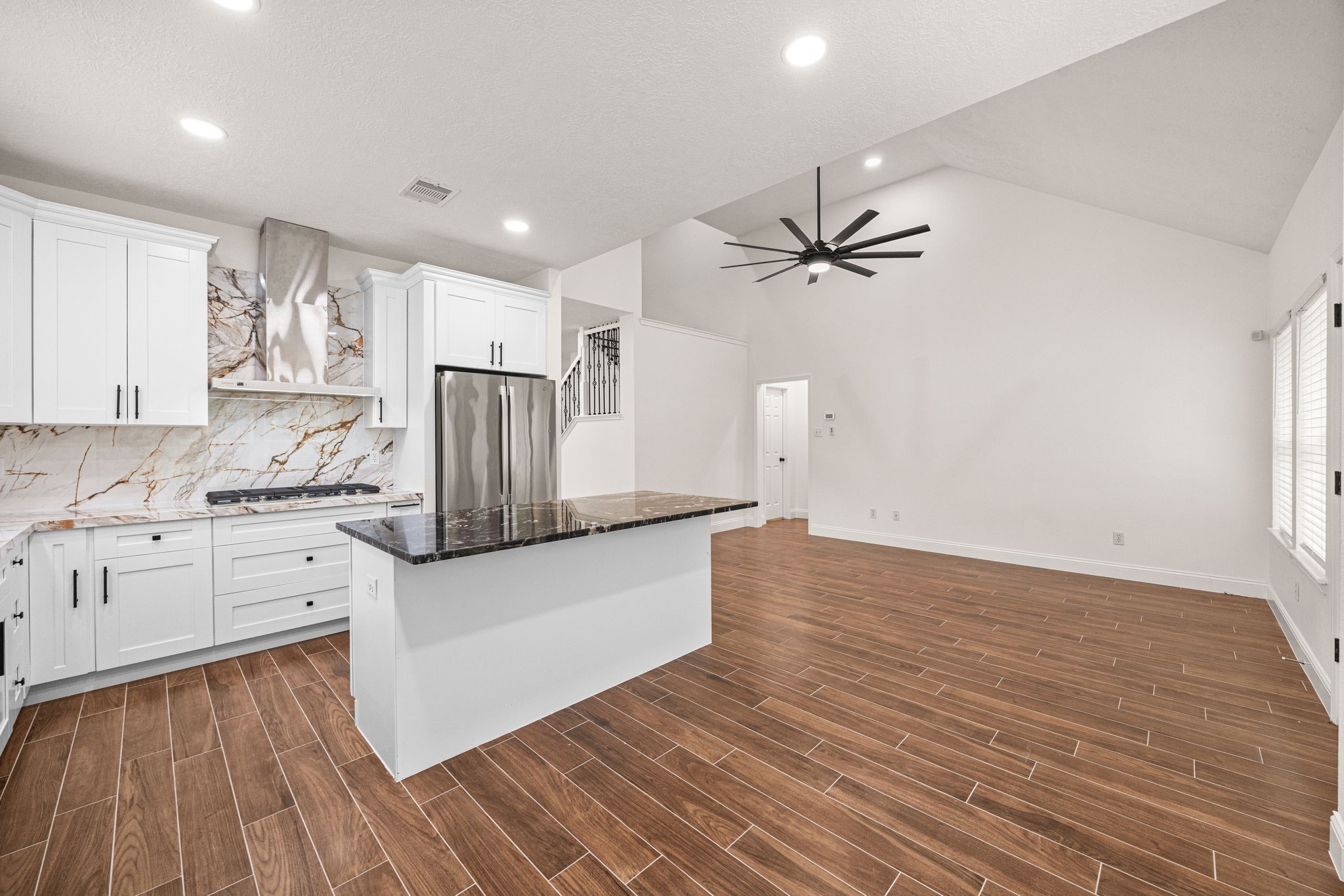 17907 Pelican Way Road Houston, TX 77084 - Photo 15 of 39 a kitchen with stainless steel appliances a white refrigerator a stove a sink and white cabinets with wooden floor next to windows