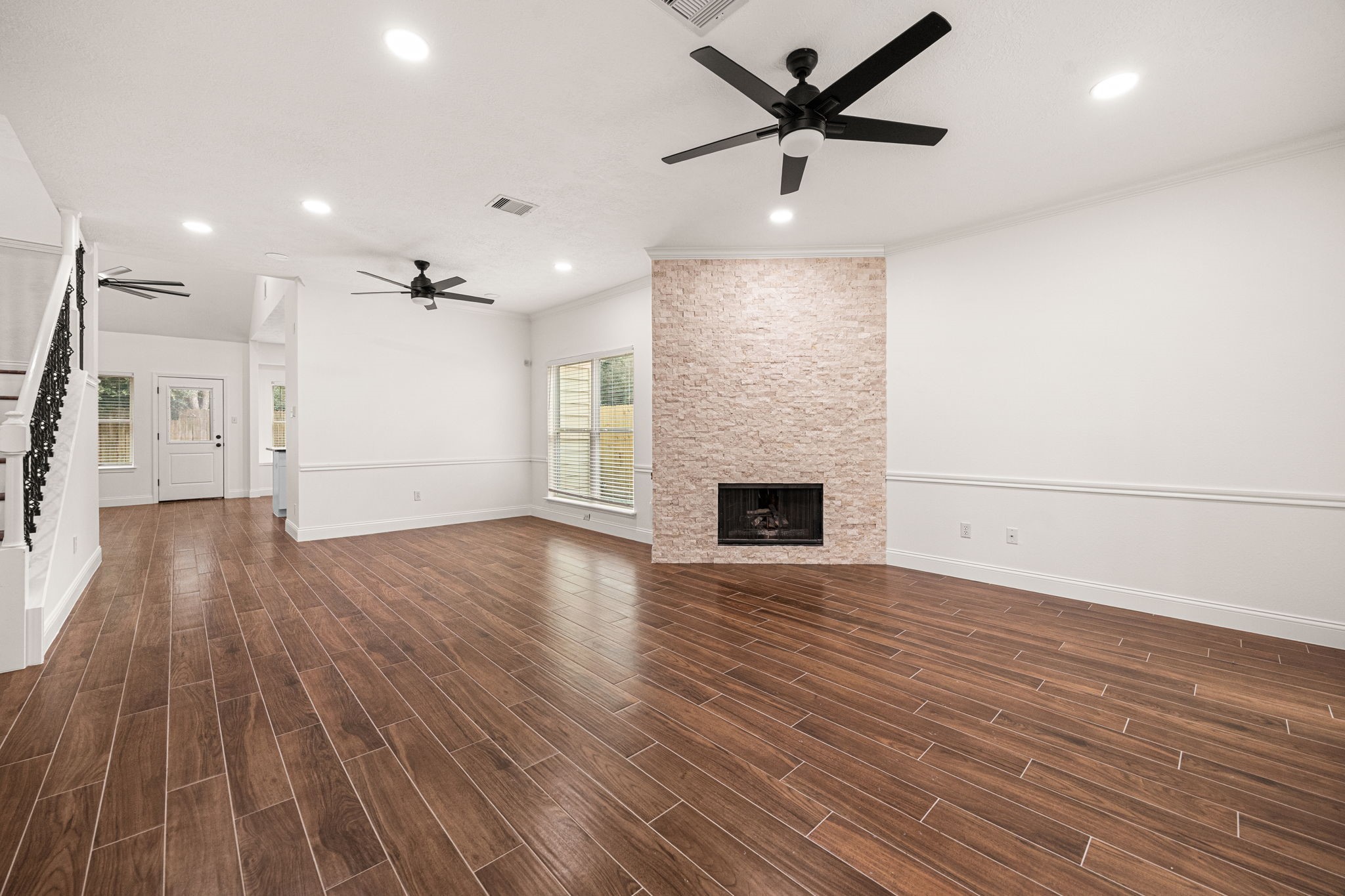 17907 Pelican Way Road Houston, TX 77084 - Photo 8 of 39 an empty room with wooden floor a ceiling fan a fireplace and windows