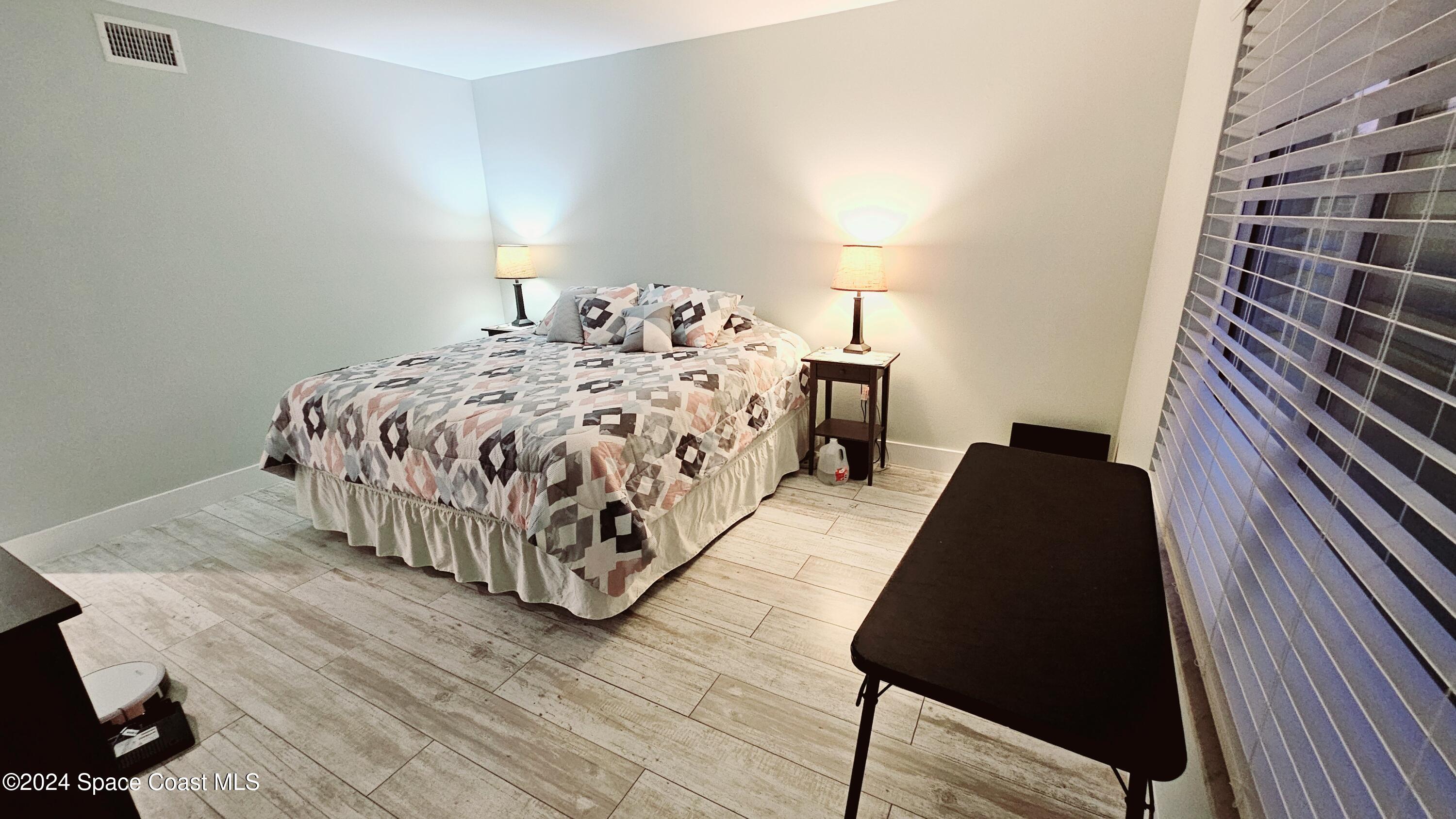 650 North Atlantic Avenue, Unit 109 Cocoa Beach, FL 32931 - Photo 16 of 36 a bed sitting in a bedroom next to a lamp