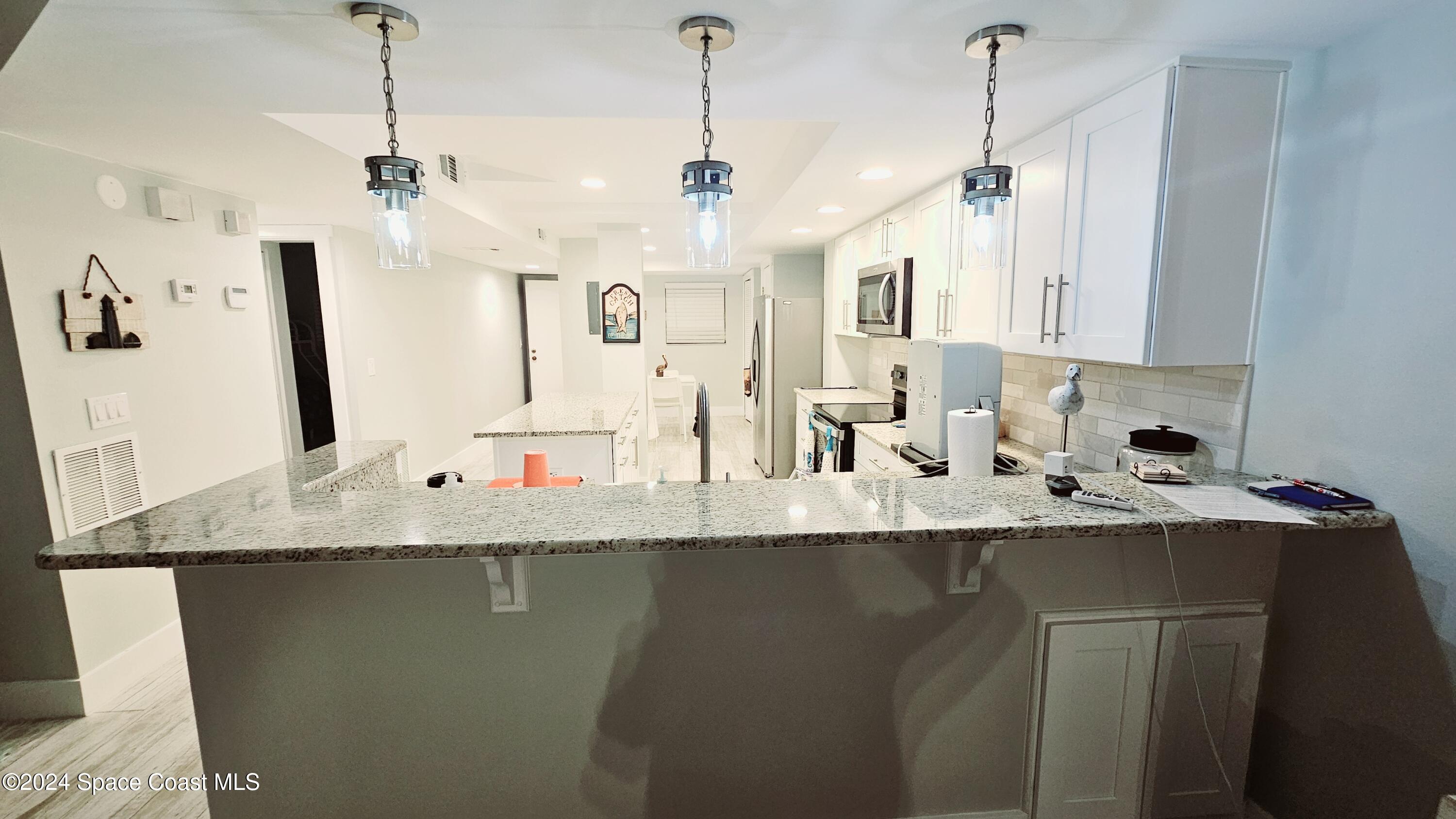 650 North Atlantic Avenue, Unit 109 Cocoa Beach, FL 32931 - Photo 10 of 36 a view of a kitchen with kitchen island a sink a counter space and appliances