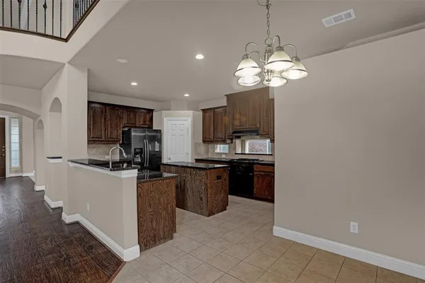 a kitchen with stainless steel appliances granite countertop a refrigerator a sink dishwasher a stove and a dining table with wooden floor
