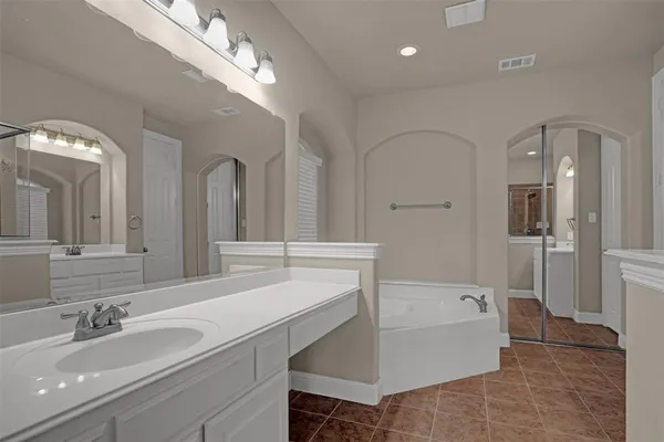 a en suite bathroom with a sink a large mirror and a bathtub