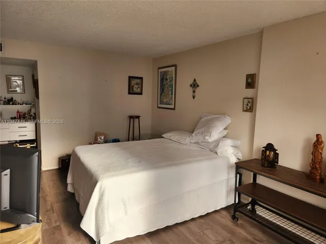 a bedroom with a bed and flat tv screen on the dresser