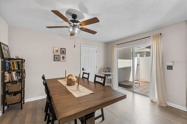 a dining room with wooden floor a chandelier fan a wooden table and chairs