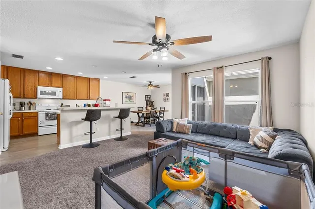 a living room with stainless steel appliances furniture and a kitchen view