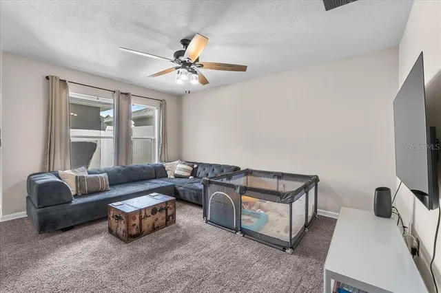 a living room with furniture a ceiling fan and a window