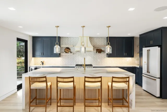 a kitchen with kitchen island granite countertop a stove a refrigerator and a sink with wooden floor