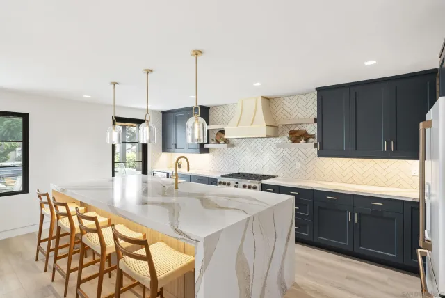 a kitchen with stainless steel appliances kitchen island granite countertop a sink a stove and a wooden cabinets