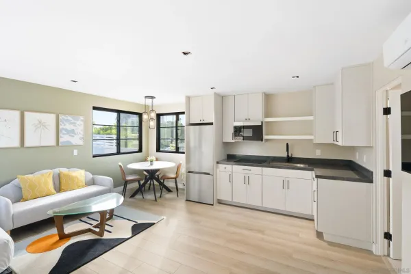 a large white kitchen with stainless steel appliances granite countertop a couch and wooden floor