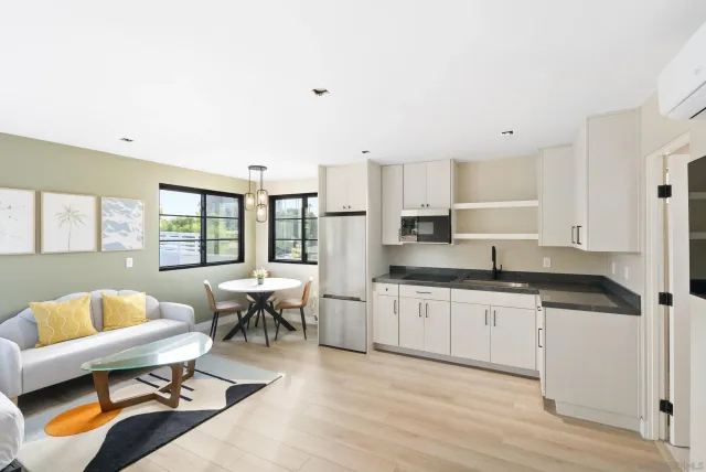 a large white kitchen with stainless steel appliances granite countertop a couch and wooden floor