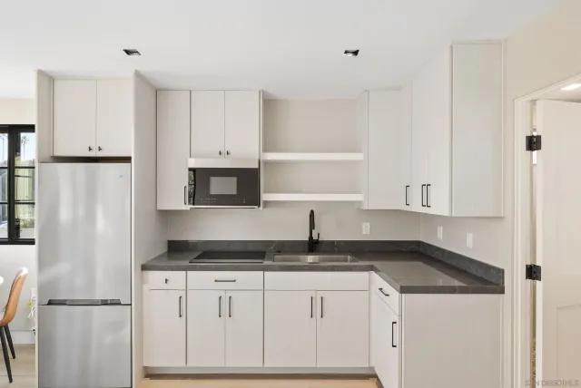 a kitchen with granite countertop white cabinets and refrigerator