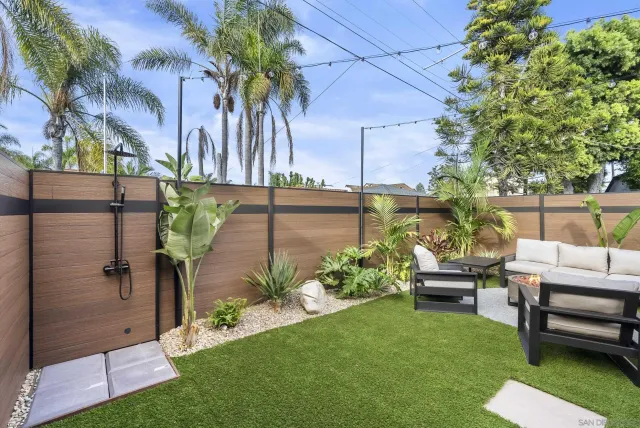 a view of a backyard with couches table and chairs and potted plants