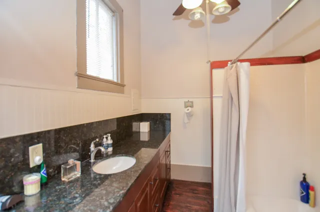 a bathroom with a granite countertop sink vanity mirror and toilet