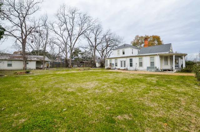 a view of a house with a big yard and large trees