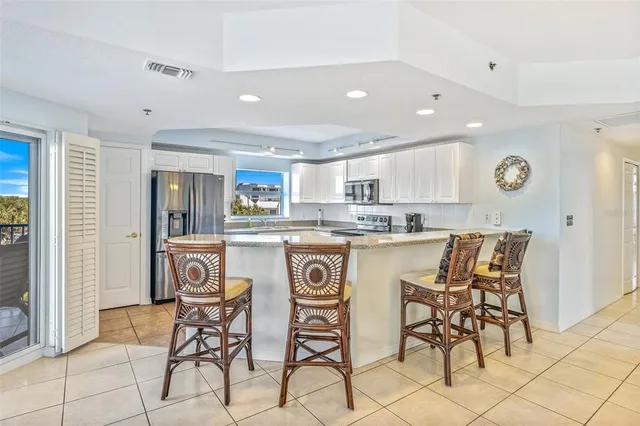 a kitchen with stainless steel appliances granite countertop a table and chairs in it