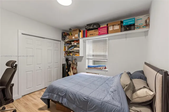 a bedroom with a bed a standing and a bookshelf