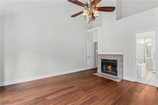 a view of an empty room with wooden floor fireplace and a window
