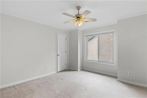 an empty room with a chandelier fan and windows