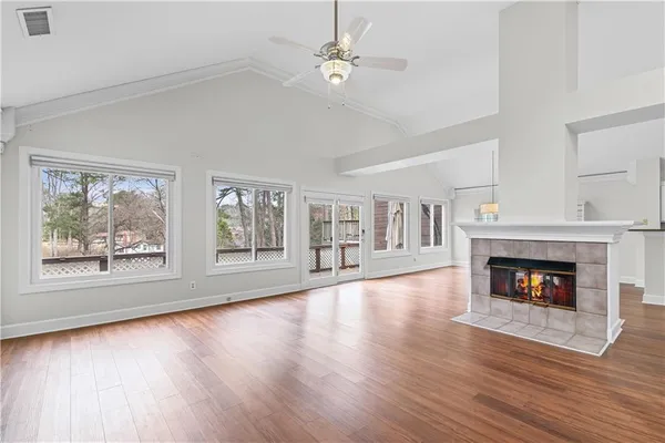 a view of an empty room with wooden floor fireplace and a window