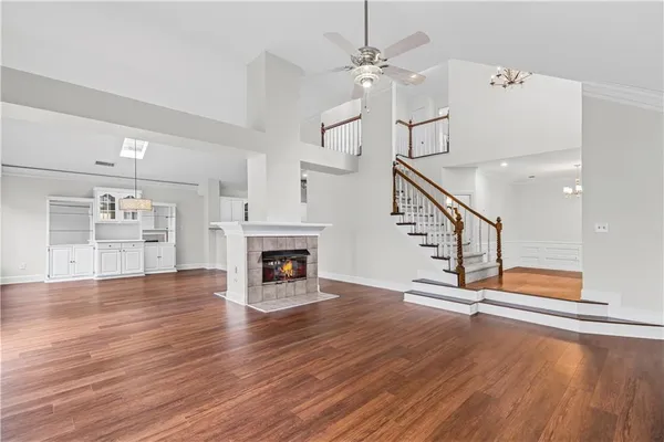 an empty room with wooden floor fireplace and windows