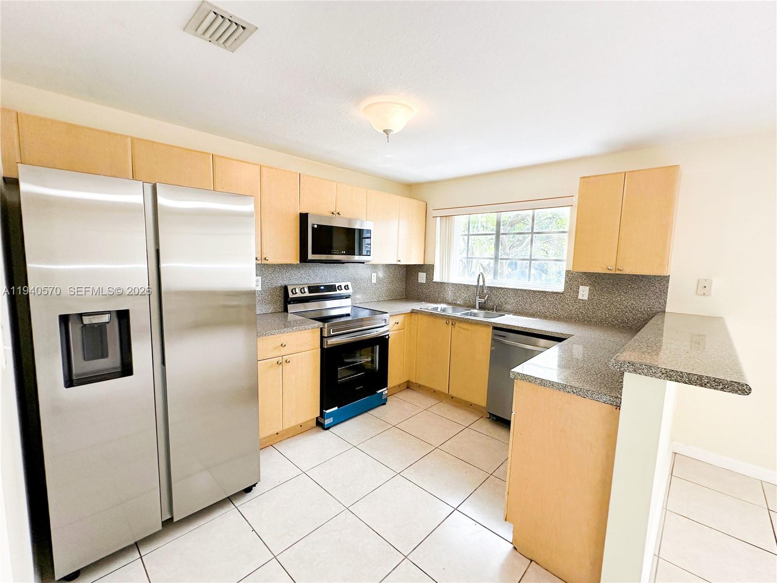 14116 Southwest 260th Street, Unit 105 Homestead, FL 33032 - Photo 8 of 30 a kitchen with stainless steel appliances granite countertop a refrigerator a stove a sink and a microwave