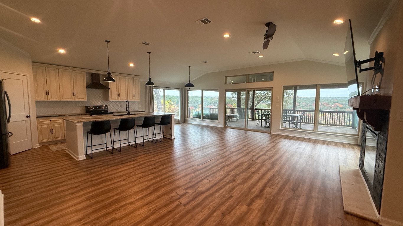 12987 Farm To Market Road 2769 Austin, TX 78726 - Photo 24 of 24 Kitchen featuring lofted ceiling, a glass covered fireplace, a breakfast bar, open floor plan, and a kitchen island with sink