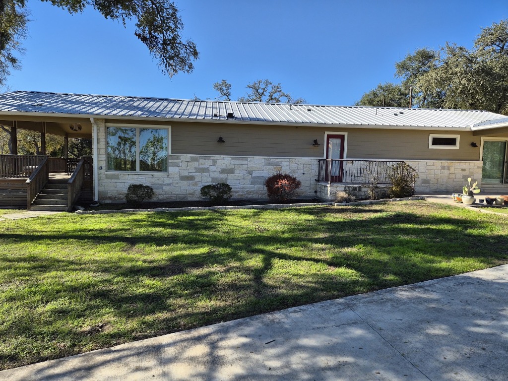 12987 Farm To Market Road 2769 Austin, TX 78726 - Photo 2 of 24 Rear view of house featuring stone siding, a metal roof, and a yard