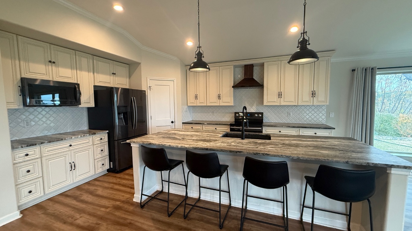 12987 Farm To Market Road 2769 Austin, TX 78726 - Photo 5 of 24 Kitchen featuring a kitchen bar, ornamental molding, dark stone countertops, a center island with sink, and decorative light fixtures