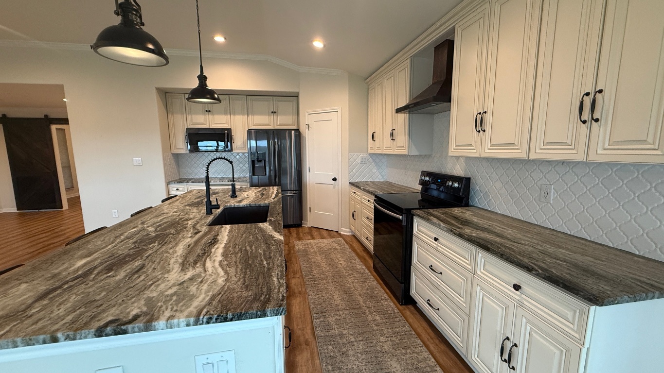12987 Farm To Market Road 2769 Austin, TX 78726 - Photo 6 of 24 Kitchen with black appliances, a barn door, wall chimney range hood, dark stone countertops, and decorative light fixtures